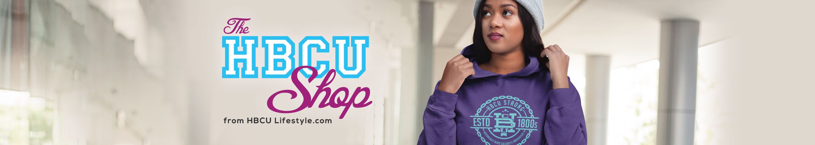 
A female graduate of a Historically Black College is wearing a purple and teal HBCU Strong hoodie in a brightly lit walkway